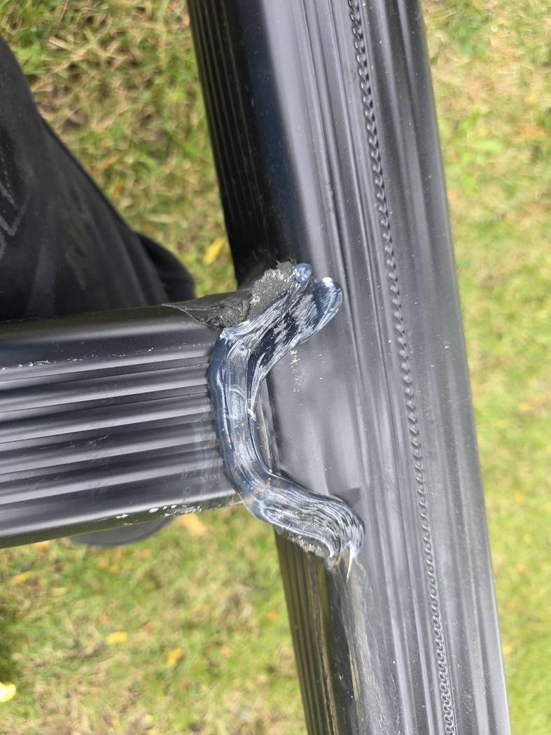 Leaking downspout Toronto: clear silicone along the seam of a T-shaped downspout joint on the lawn, applied by DT Cleaning, September 2026