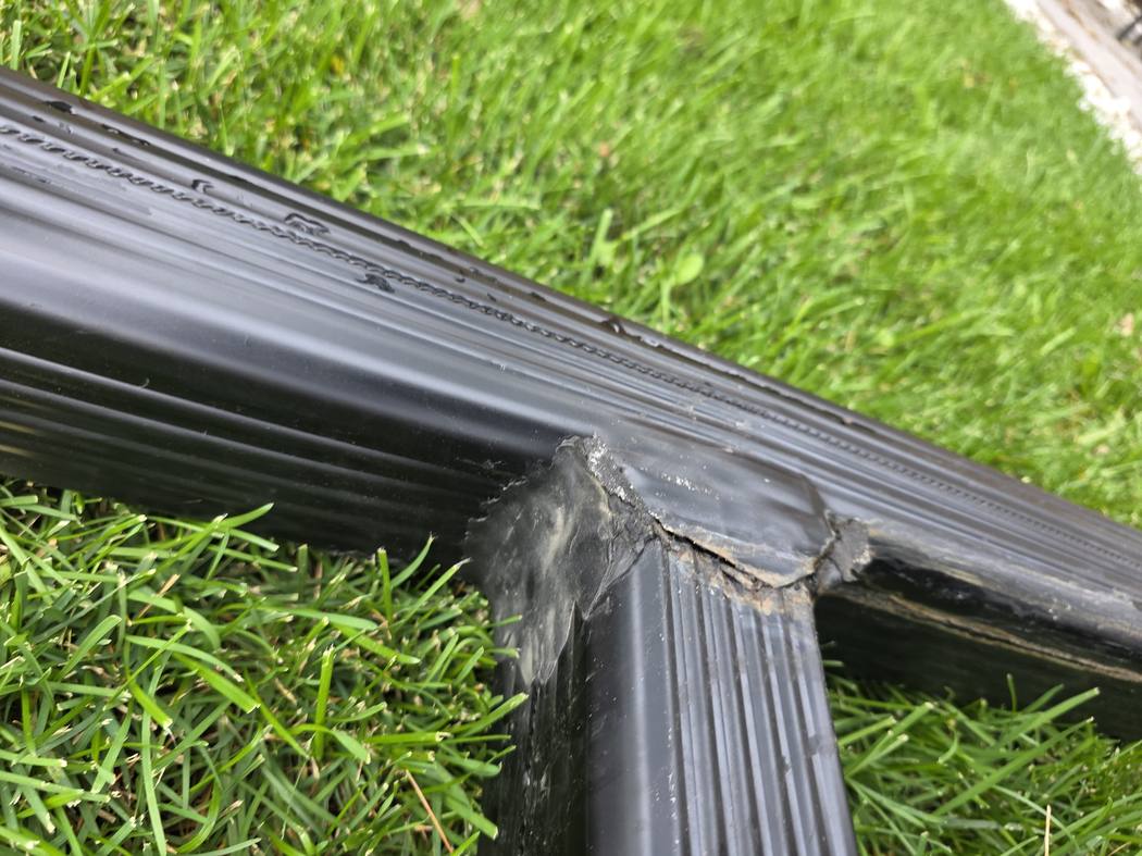 T-shaped downspout joint on a lawn in Toronto with a dirty, split seam where the two downspouts meet