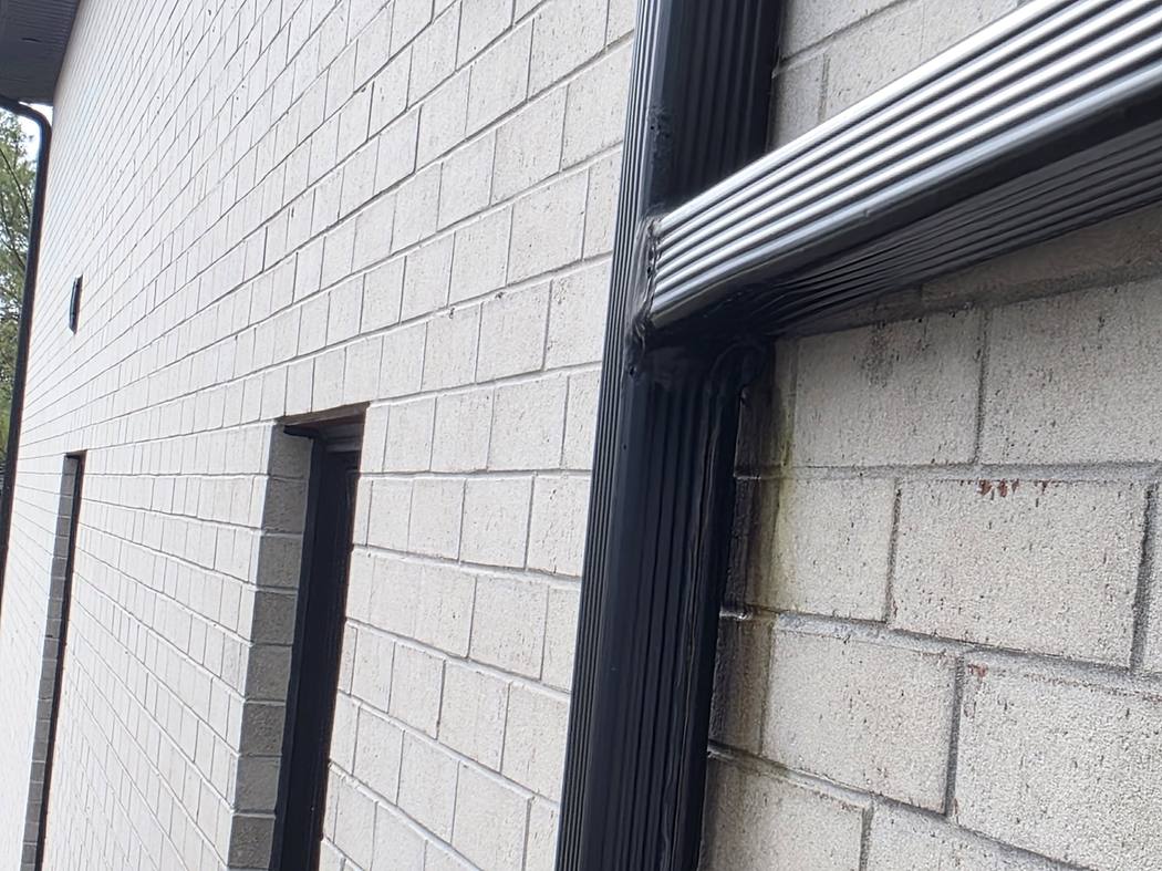 Leaking downspout Toronto: dark staining on the brick below a T-shaped downspout joint, photographed by DT Cleaning, September 2026