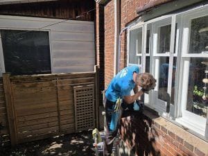 Storm window cleaning Toronto: a DT Cleaning technician on a ladder at a storm window frame on a brick house in Etobicoke, September 2026