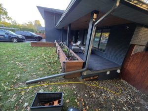 Downspout installation Etobicoke: a new grey downspout down a black porch post with a long extension, the DT Cleaning van on the driveway