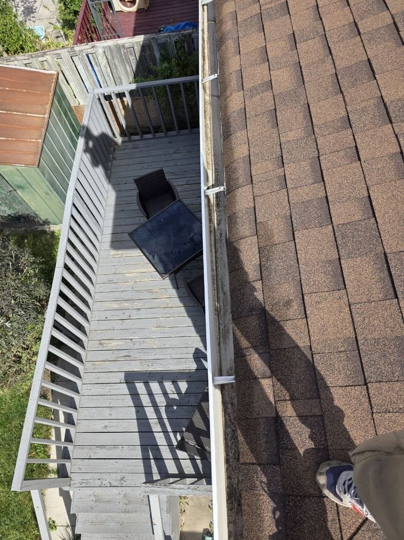 The eavestrough above a grey wooden deck in Mississauga, empty, with brackets across the trough