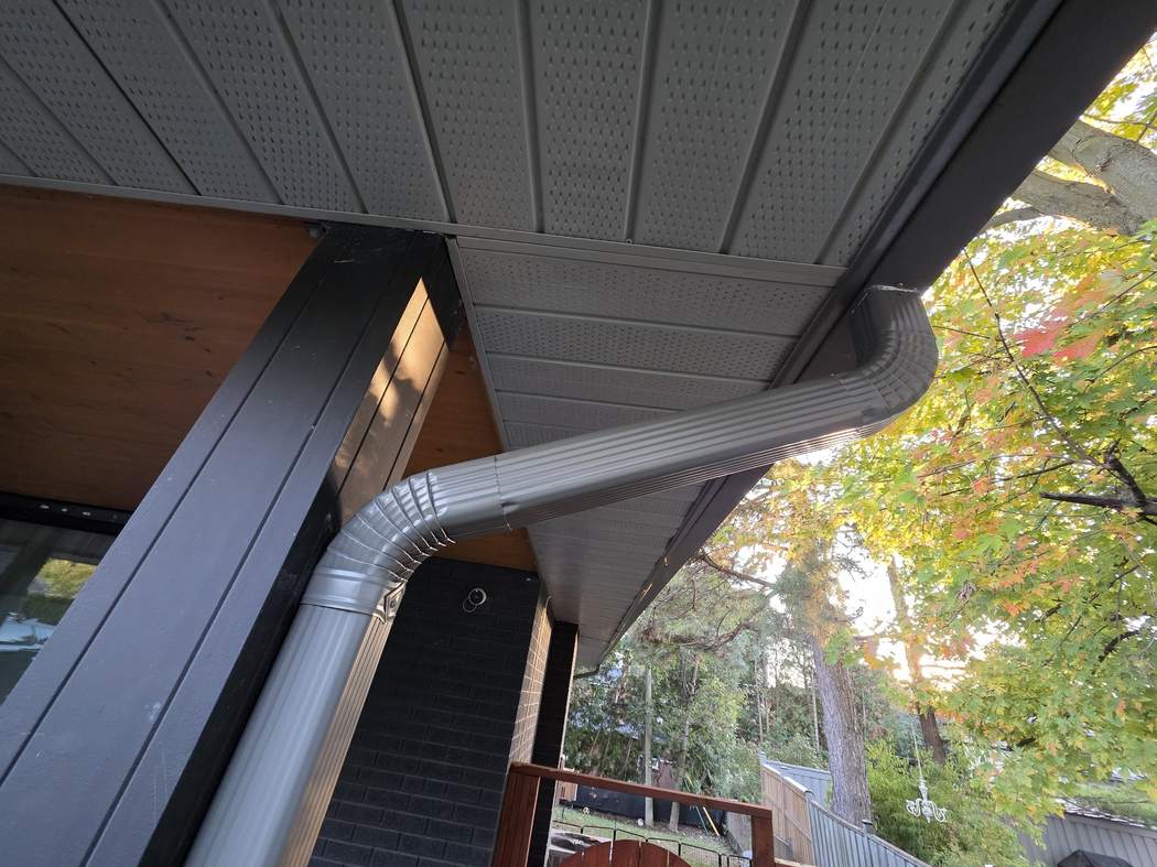 New downspout through offset elbows at the porch, Etobicoke Downspout installation Etobicoke: the new grey downspout bending through offset elbows under the porch soffit and down a black post